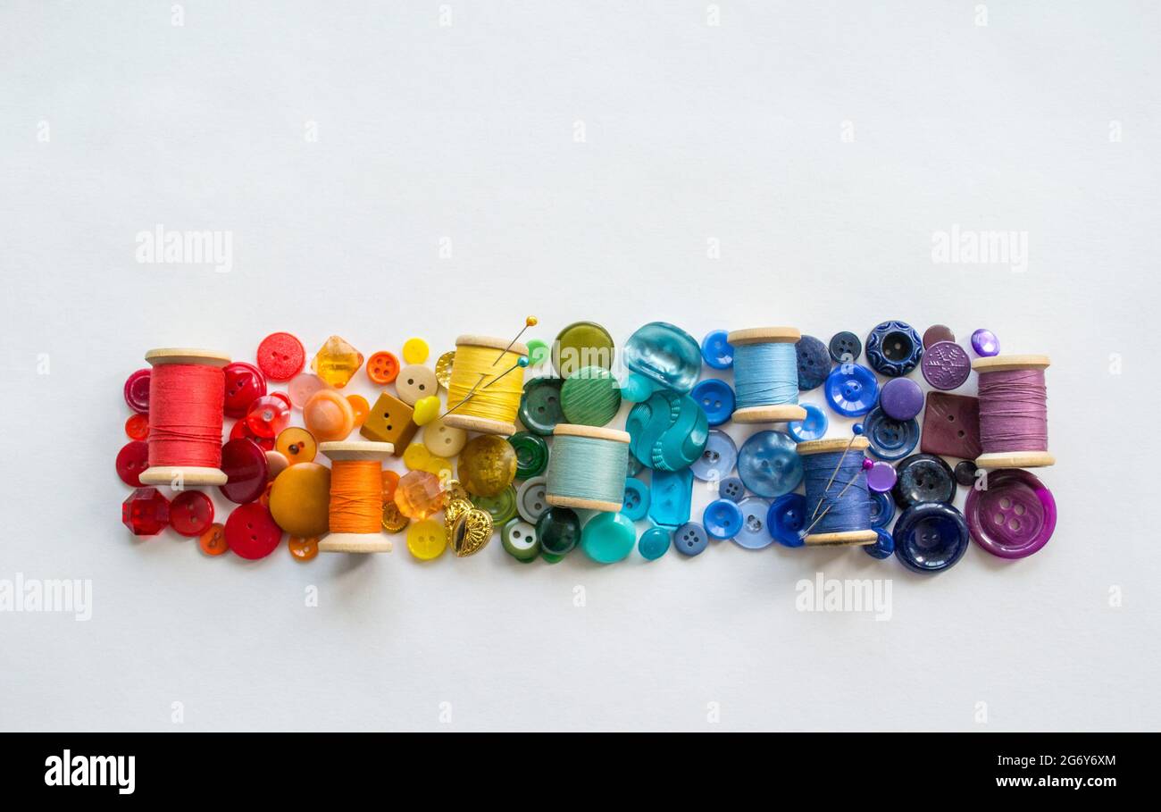 A lot of buttons and reels with colorful threads, laid out on a white ...