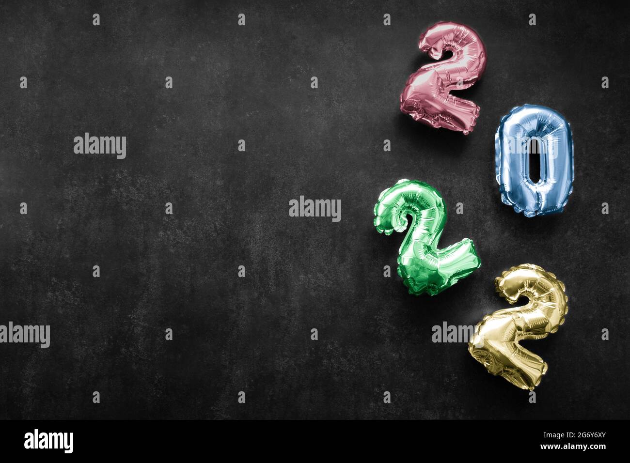 Inflatable shiny colorful numbers red, blue, green, yellow color of the new year 2022 on a dark grey or black background. Copy space. Stock Photo