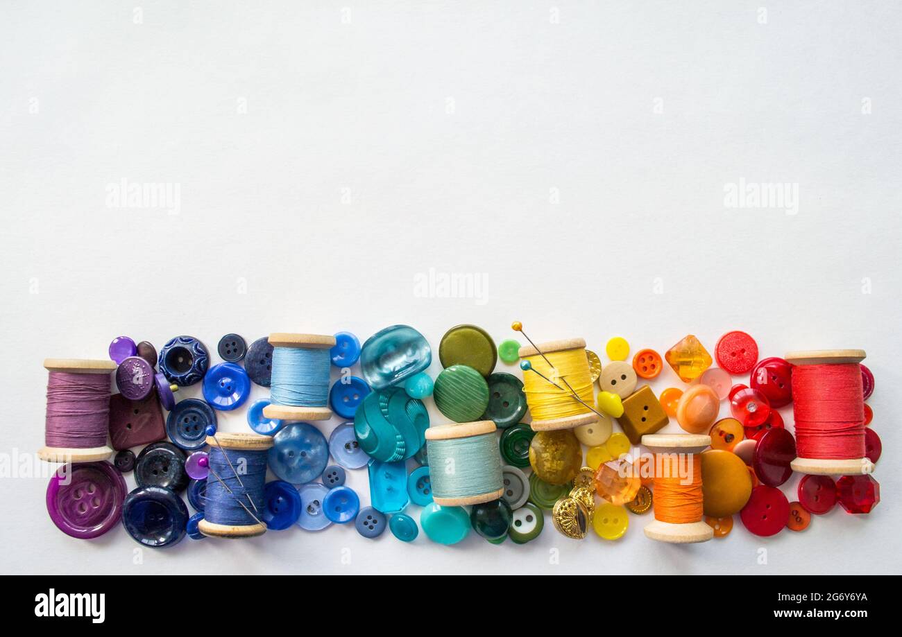 A lot of buttons and reels with colorful threads, laid out on a white ...