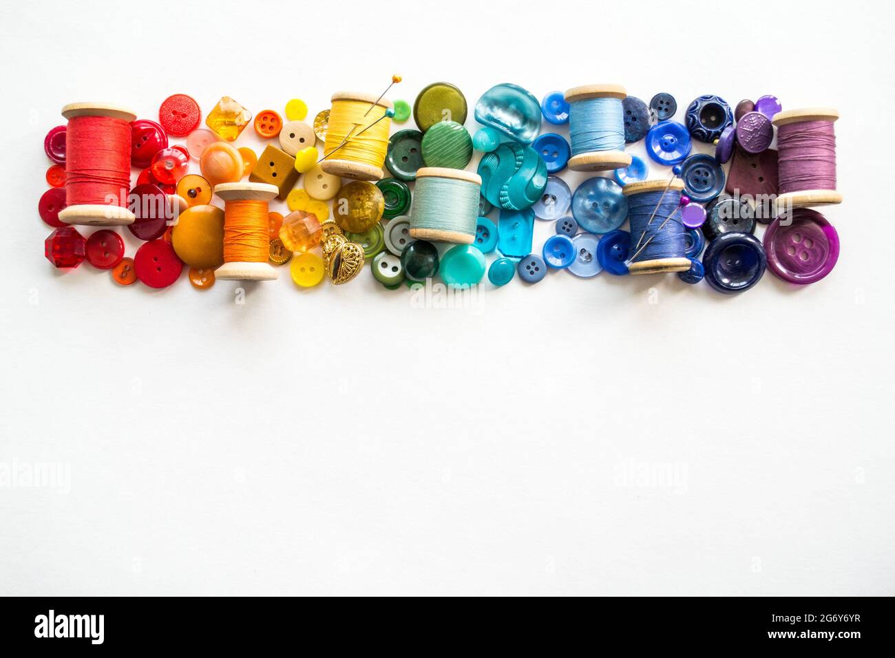 A lot of buttons and reels with colorful threads, laid out on a white ...
