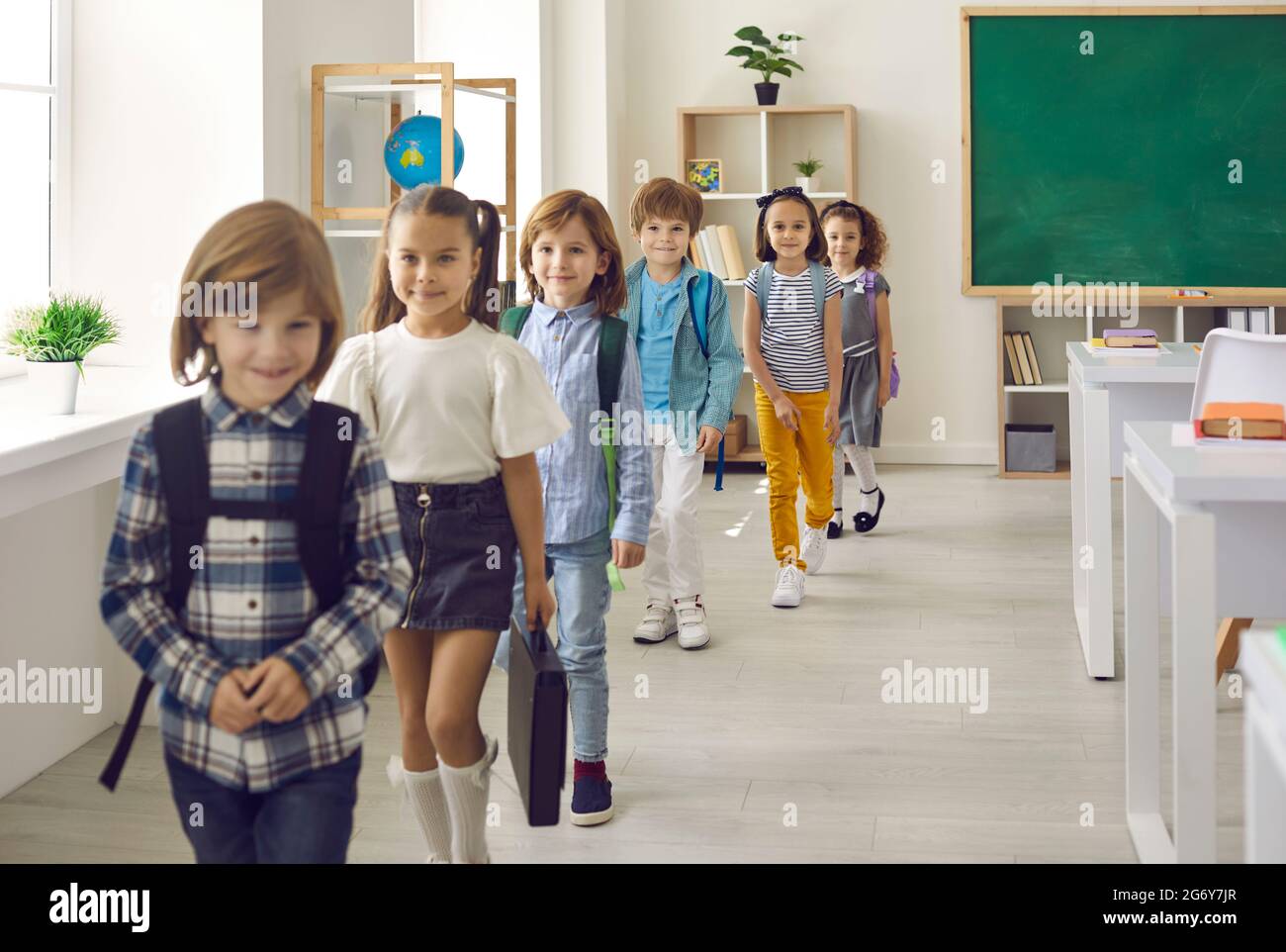 Small group of happy elementary school students leaving their classroom after a lesson Stock Photo