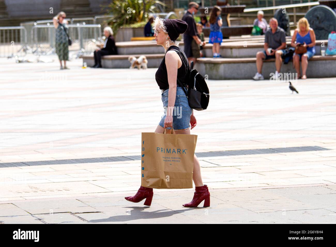 Dundee, Tayside, Scotland, UK. 9th July, 2021. UK Weather: Humid day with a warm breeze and sunny intervals across North East Scotland with temperatures reaching 18°C. A young fashionable woman with red boots holding a Primark fashion retail store paper carrier bag after a day out shopping in Dundee city centre. Credit: Dundee Photographics/Alamy Live News Stock Photo