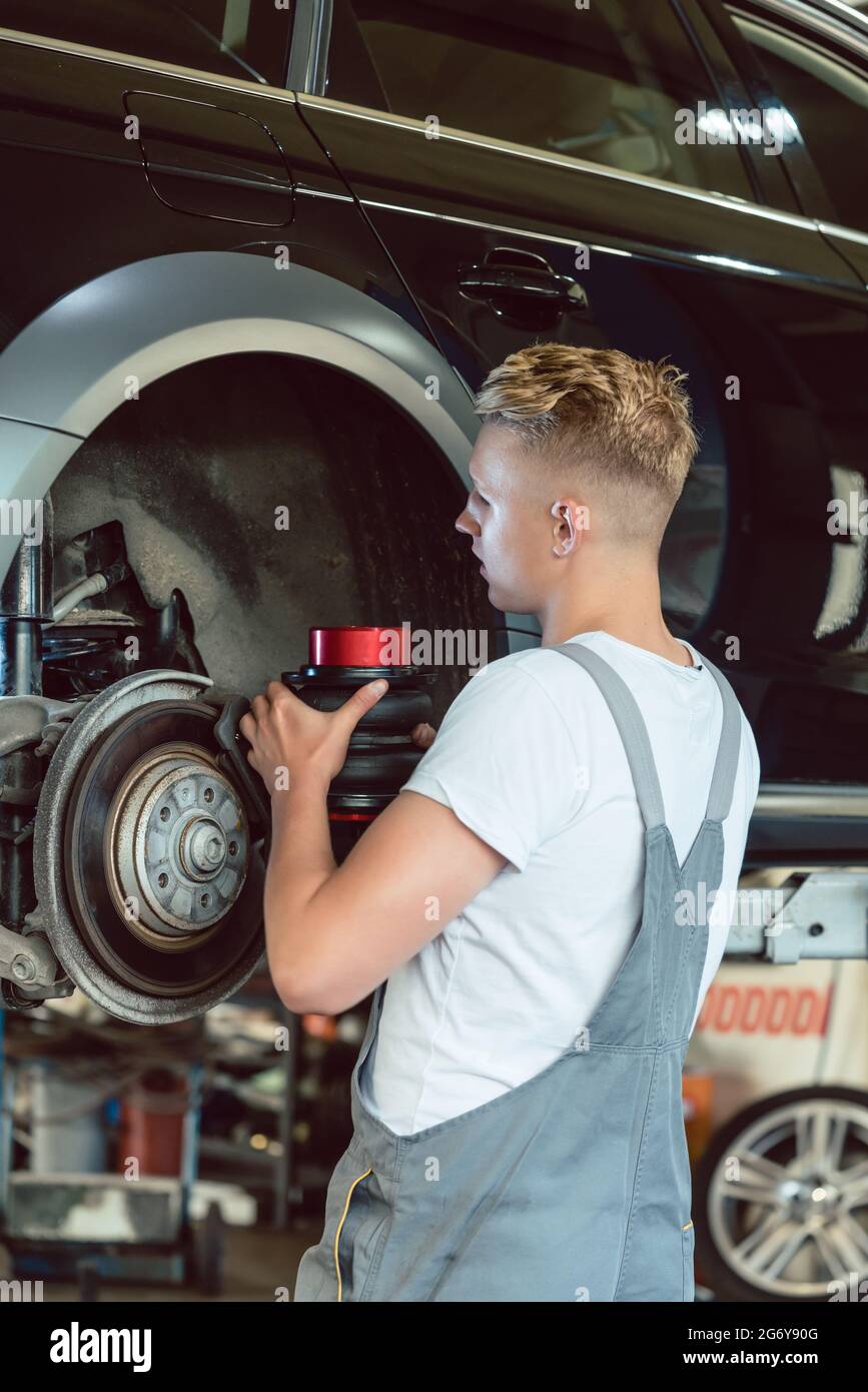 Experienced auto mechanic replacing the disk brakes of a lifted car