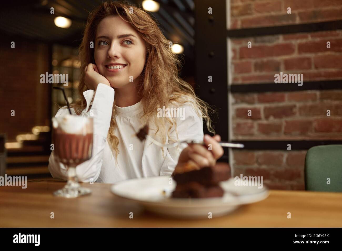 Pretty woman sitting at cafe with dessert and coffee Stock Photo