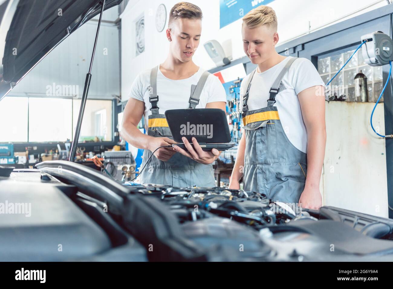 Experienced auto mechanic using a laptop for scanning and interpreting ...