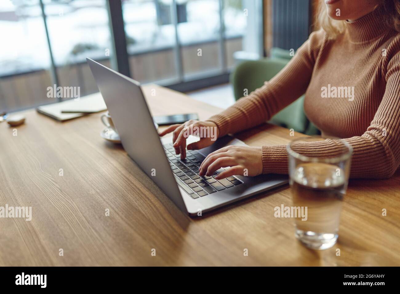Woman typing on laptop while working remotely from cafe Stock Photo