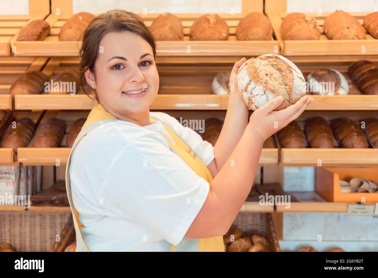 Saleslady in bakery shop presenting bread to potential buyer Stock Photo