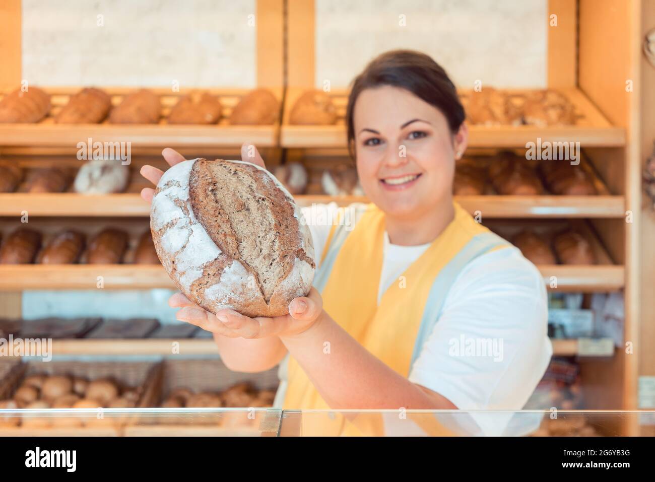 Saleslady in bakery shop presenting bread to potential buyer Stock Photo
