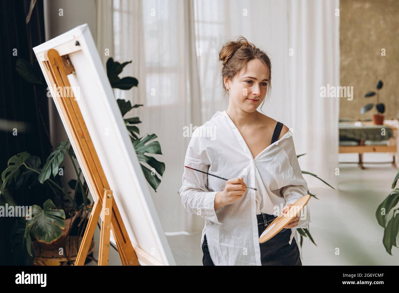 Woman holding paintbrush and color palette in studio Stock Photo