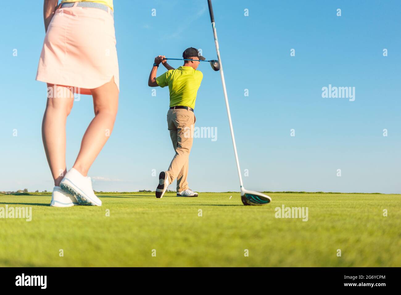 Low-angle full length view of man playing professional golf with his female partner during matchplay, for two players outdoors in a sunny day of summe Stock Photo