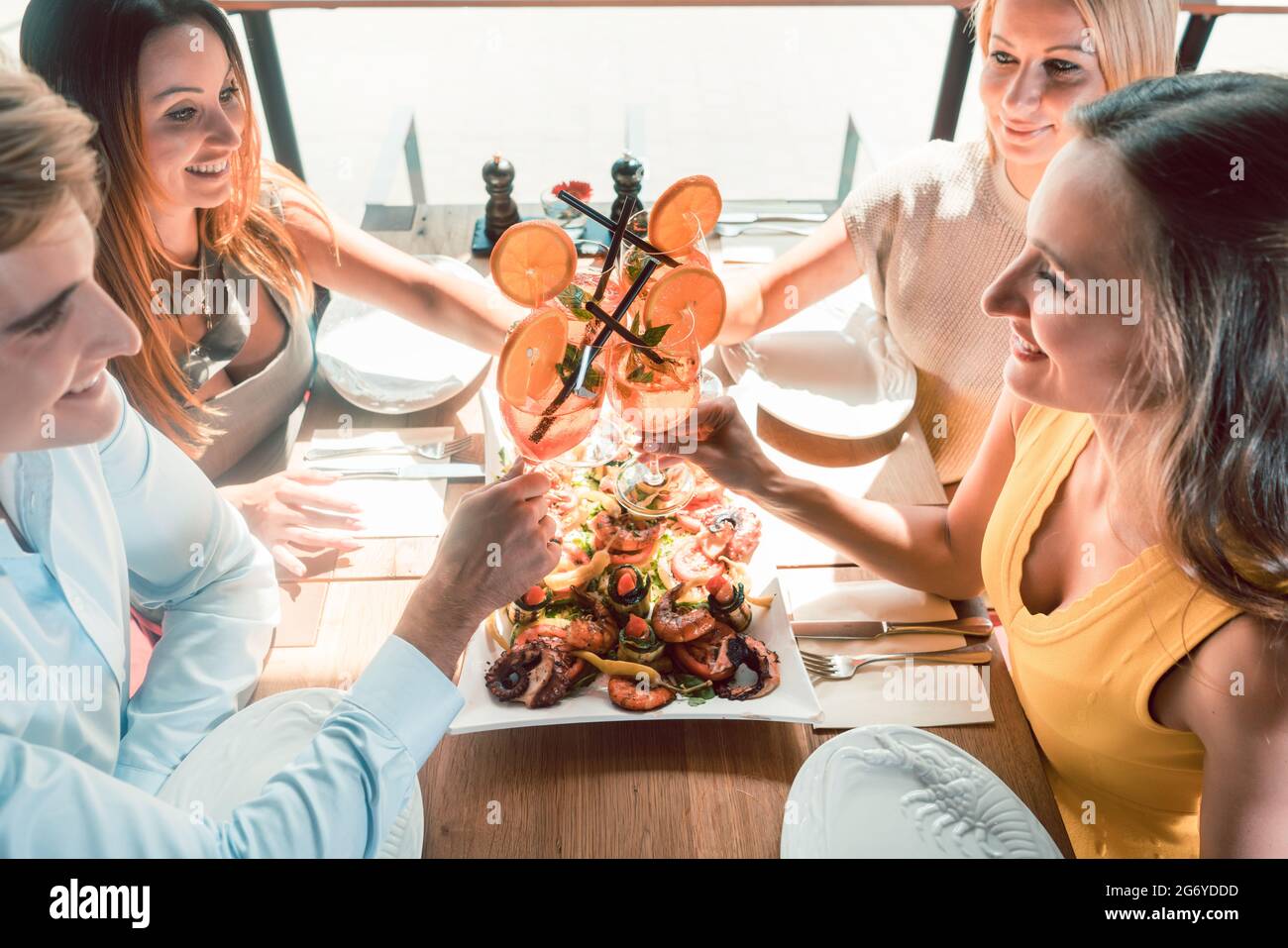 Highangle view of the hands of four young friends toasting with fresh