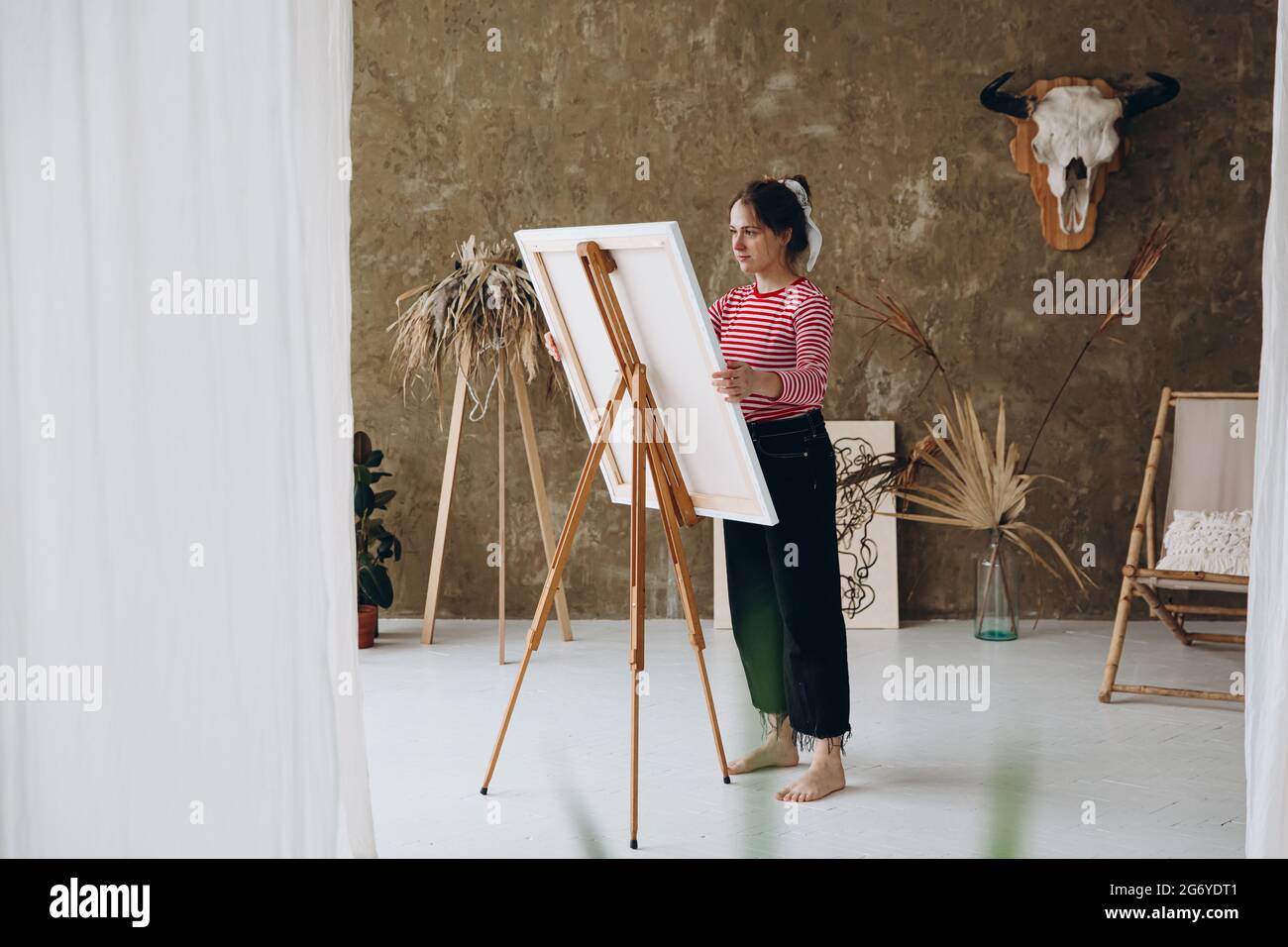 Woman standing in front of easel and painting with brush Stock Photo ...