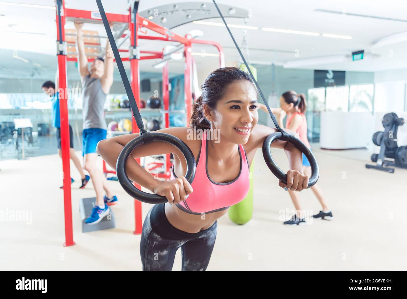 Cheerful fit young woman exercising with gymnastic rings during routine