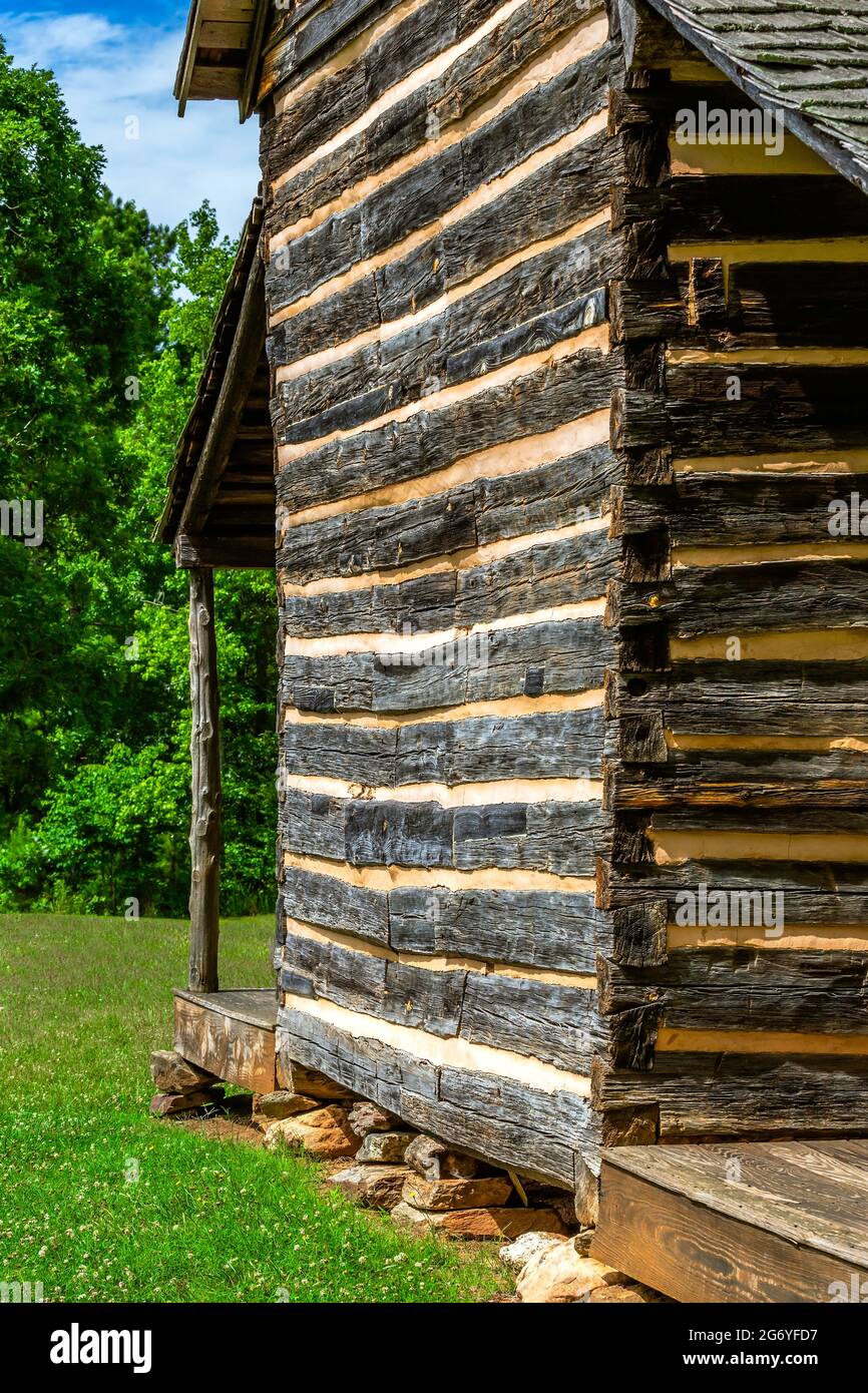 Log cabin with dovetail notches and chinking. Piled stones are used for a foundation base creating the need splash zone for the house.  Robert Scruggs Stock Photo