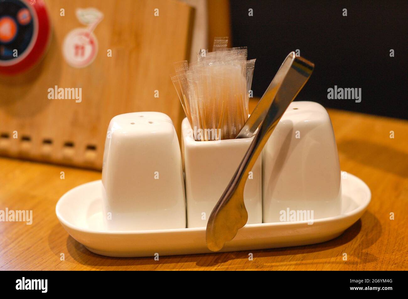 stand porcelain salt, pepper, sugar tongs, toothpicks, call the waiter  button on a wooden table Stock Photo - Alamy