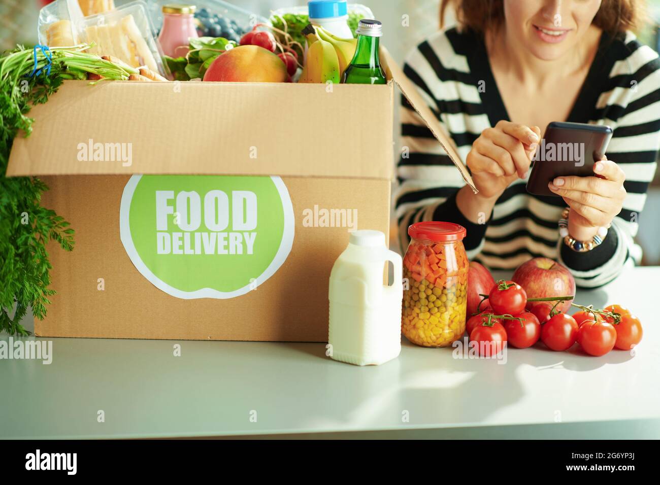Food delivery. Closeup on happy female with food box using smartphone