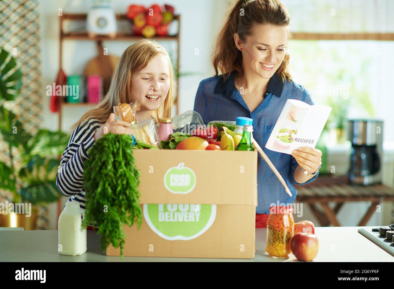 Food delivery. happy modern mother and daughter with food box and
