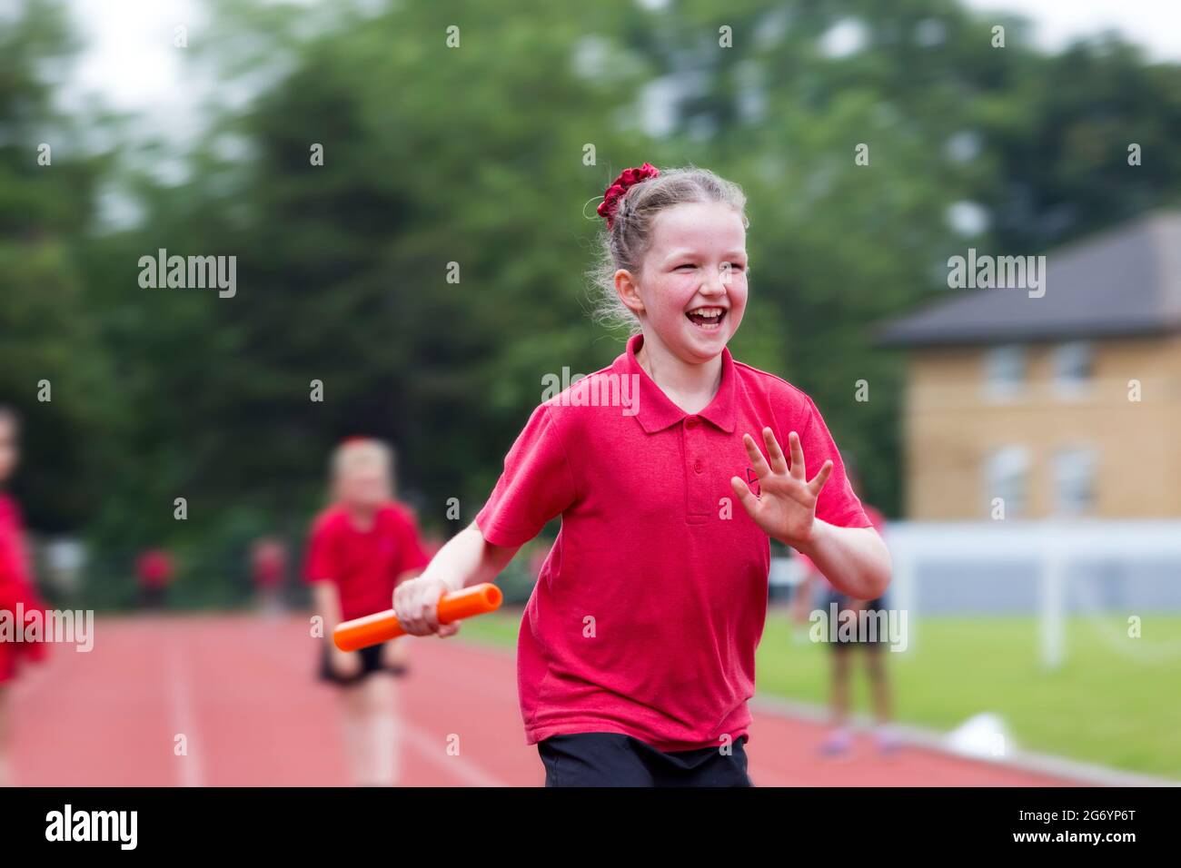 Primary year 4 school girl child / kid takes part in relay running race / sport on school sports day / summers / academic year / schools term end. Stock Photo