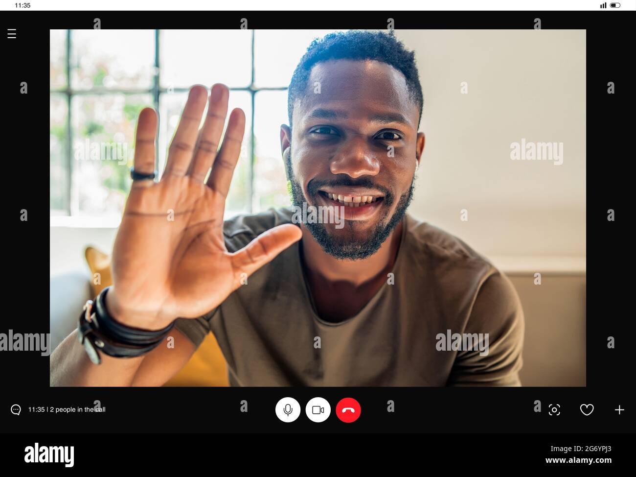 Young man saying hello to someone while having a video call at home. Stock Photo