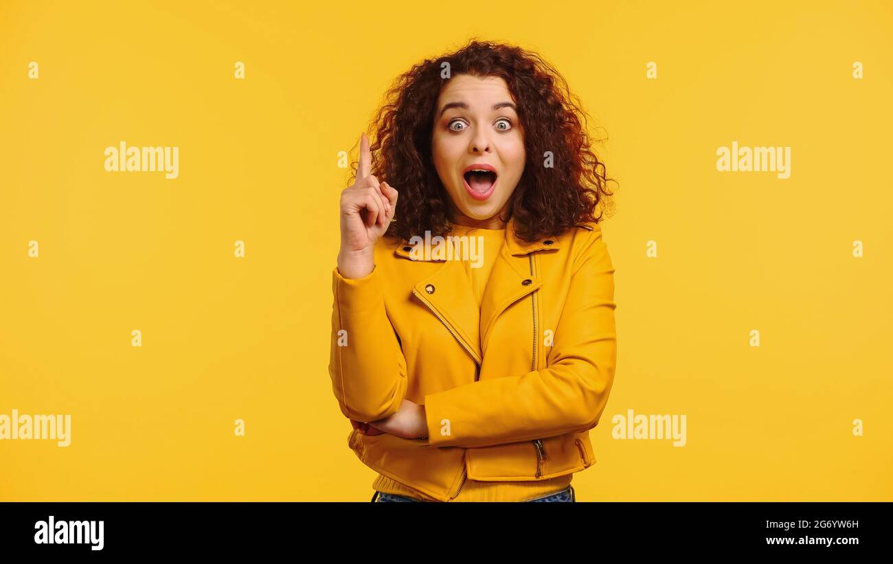 amazed young woman in leather jacket having idea isolated on yellow Stock Photo