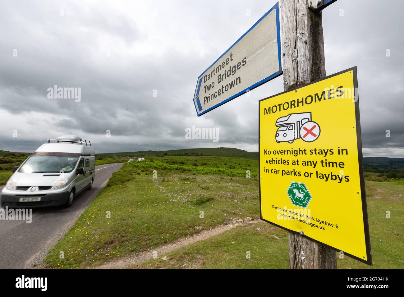 A motorhome pictured travelling along a rural road through Dartmoor National Park in Devon, UK past a sign. Stock Photo