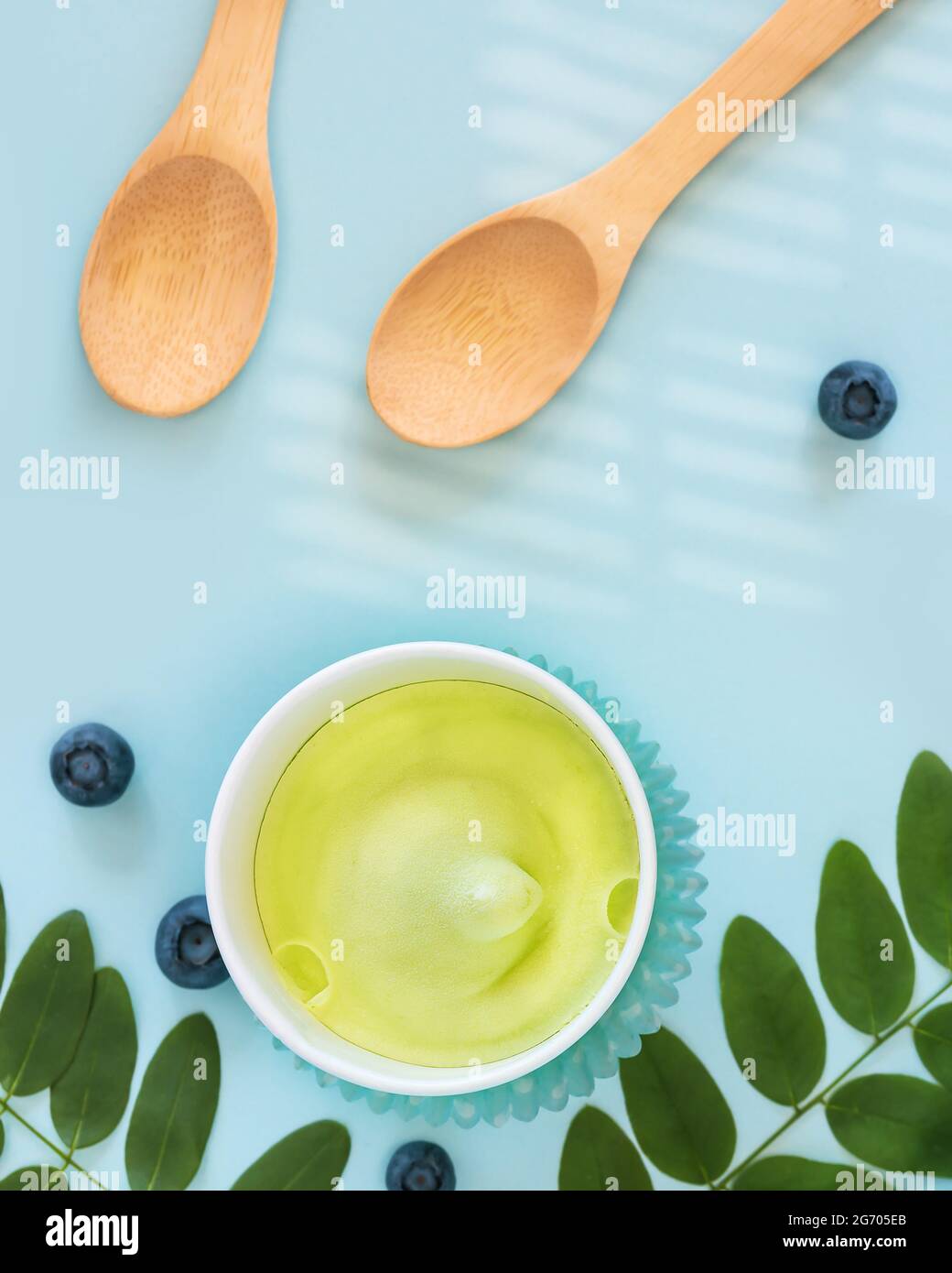 Summer, food composition with natural, vegan ice cream, blueberries, leaves and wooden spoons on a blue background. Eco friendly still life with fruit Stock Photo