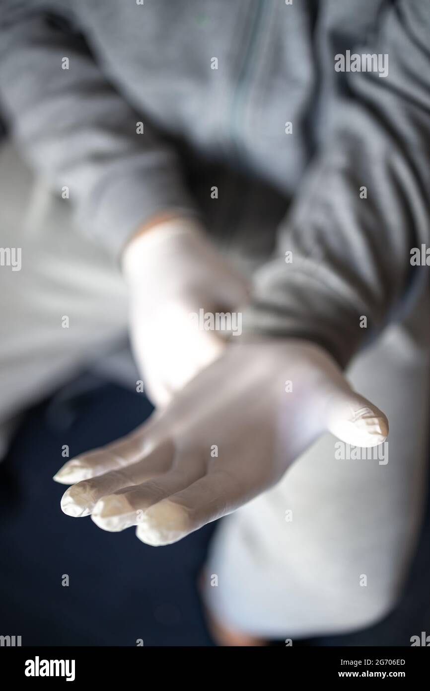 Man in gray clothes putting on medical latex gloves. The concept, prevention and protection against coronovirus infection. Stock Photo