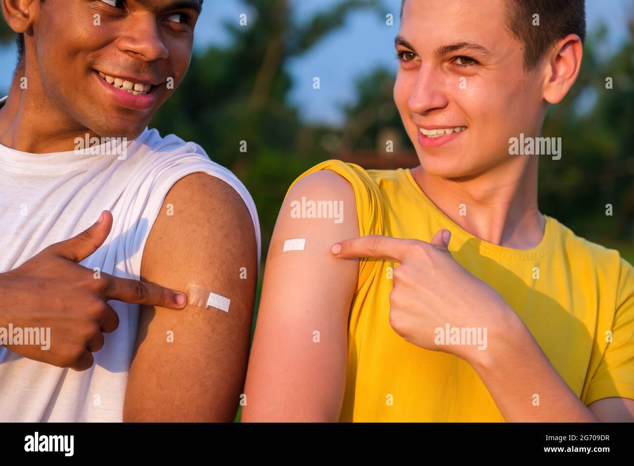 Two african american and caucasian friends showing their hands after vaccination Stock Photo
