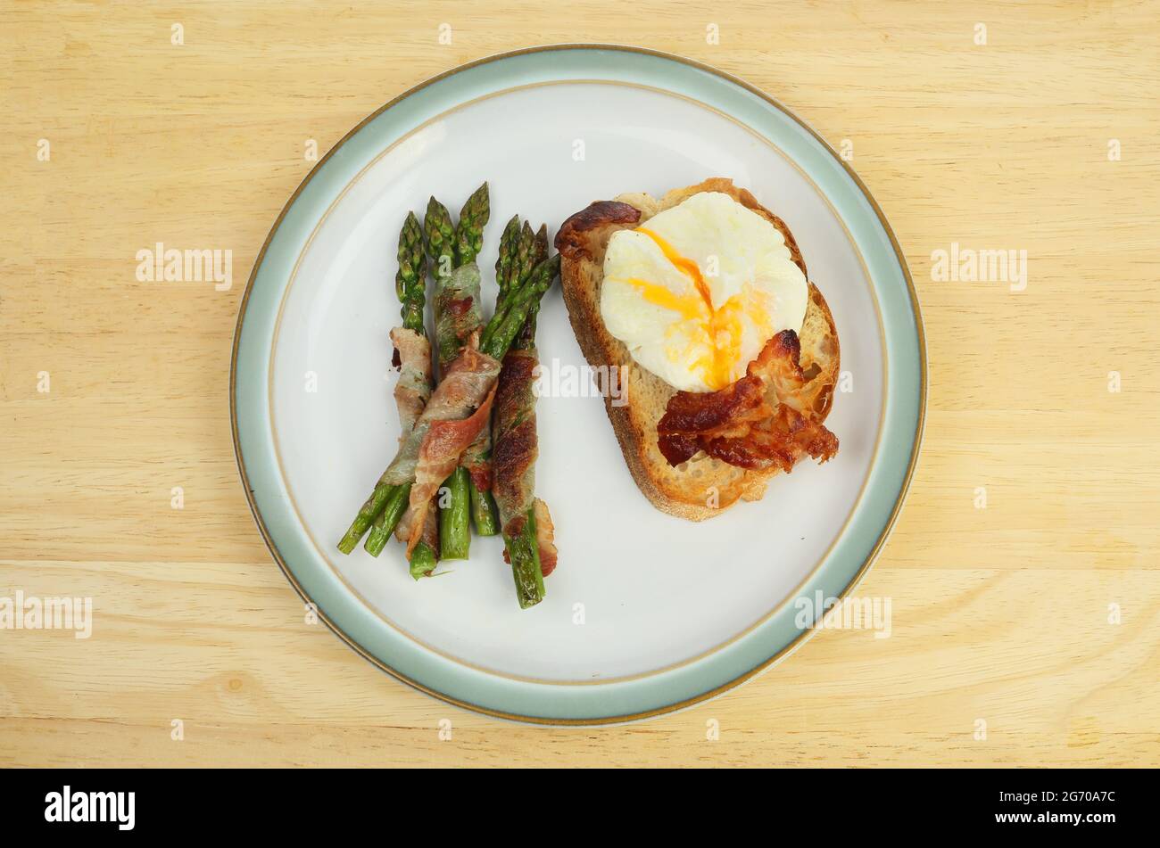 https://c8.alamy.com/comp/2G70A7C/poached-egg-on-toast-with-pancetta-wrapped-asparagus-on-a-wooden-tabletop-2G70A7C.jpg