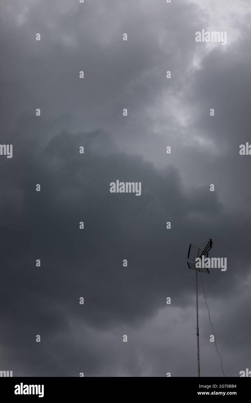 dark, grey, cloudy, sky before the storm and rooftop with metal antenna Stock Photo