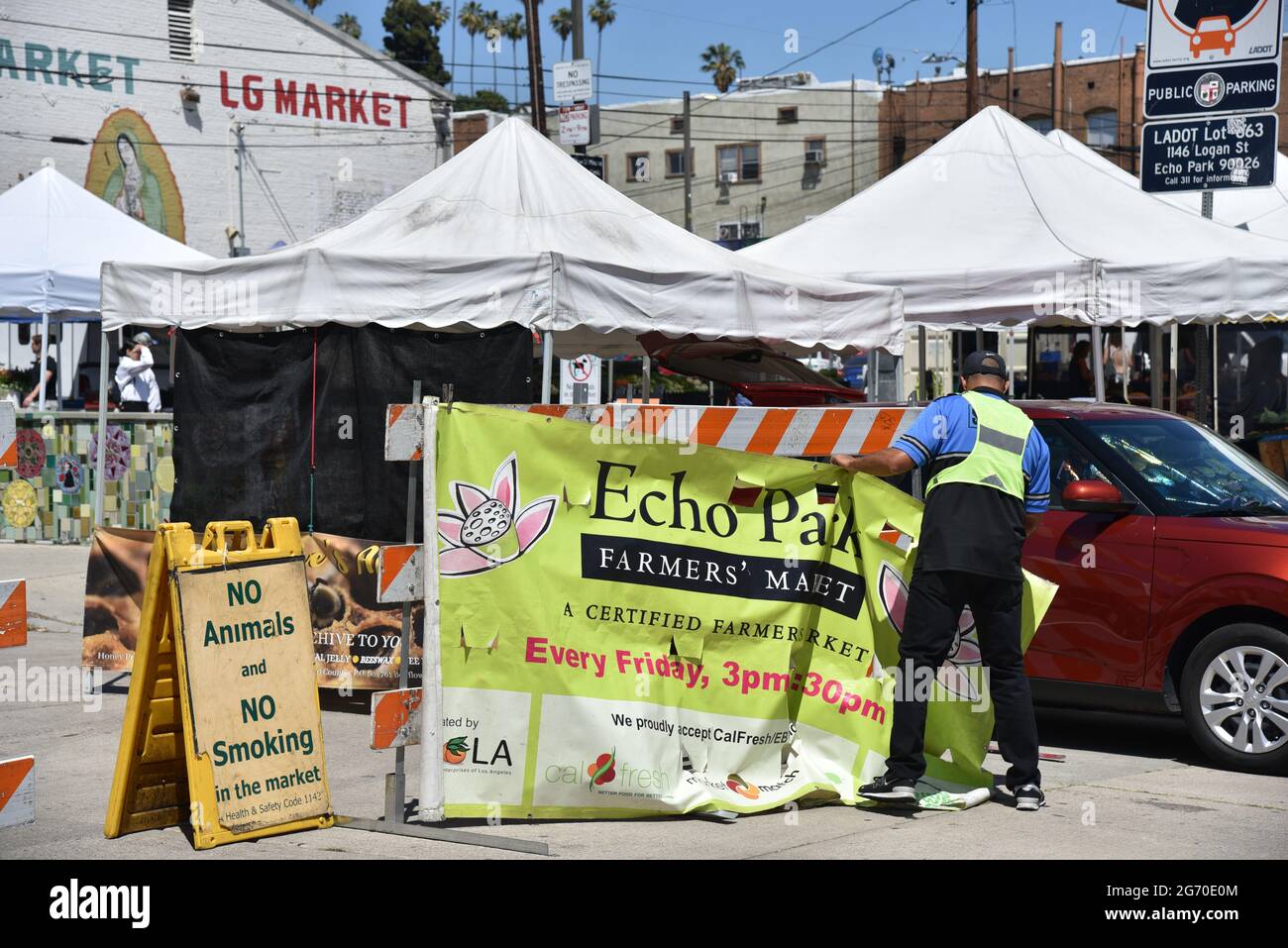 Los Angeles, CA USA - June 24, 2021: Man hanging banner for the Echo Park Farmers Market at the entrance Stock Photo