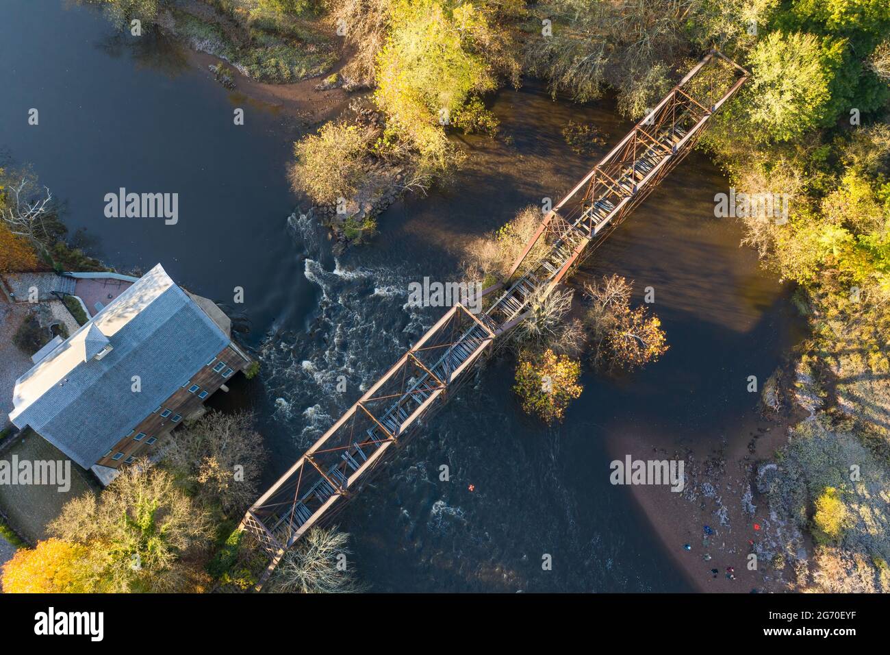 Aerial of the roof of an old, abandoned mill on a river in New Jersey with train tracks over the river, in Autumn. Stock Photo