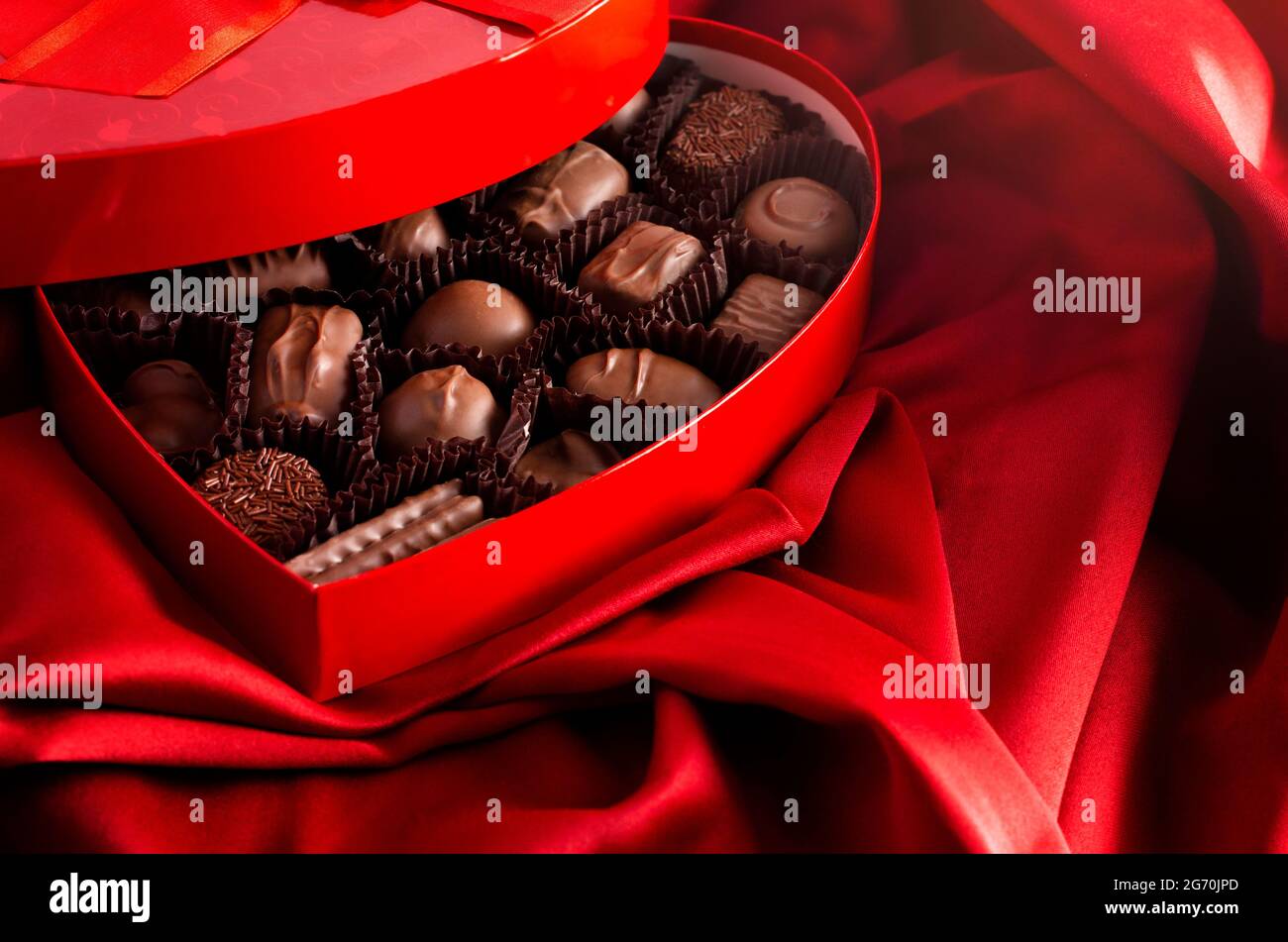 Box Of Milk Chocolates In A Red Love Heart On A Bed With Red Sil