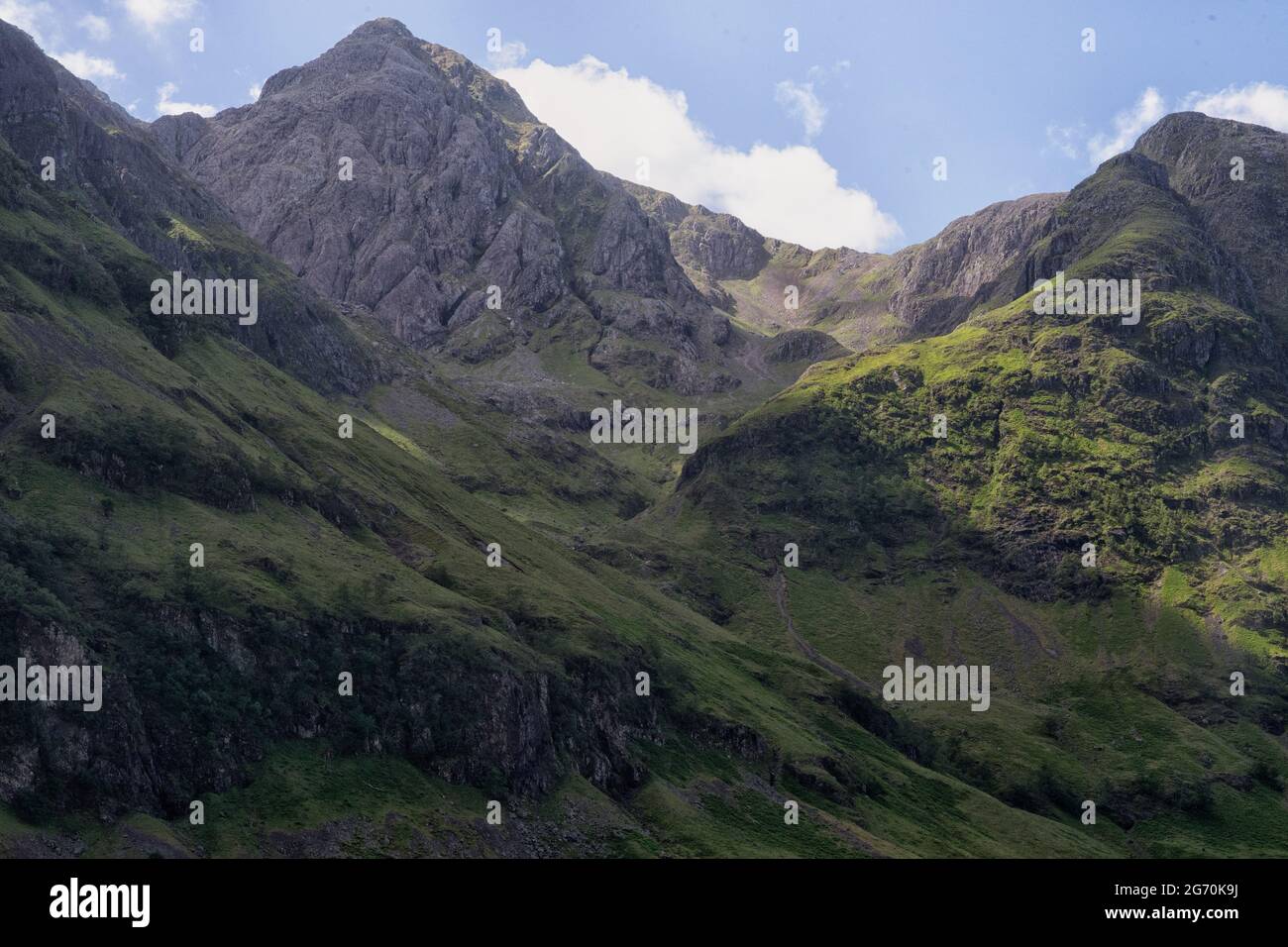 Track leading up a valley towards an exposed mountain peak Stock Photo