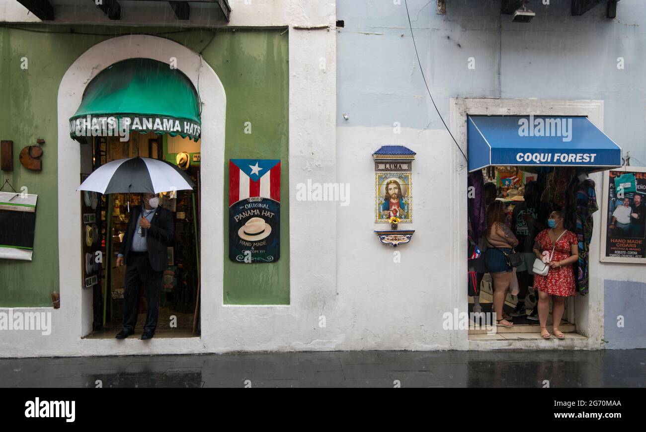 Shops on Calle De La Fortaleza and portrait of Jesus Christ during a heavy afternoon rain in old San Juan, Puerto Rico, USA. Stock Photo