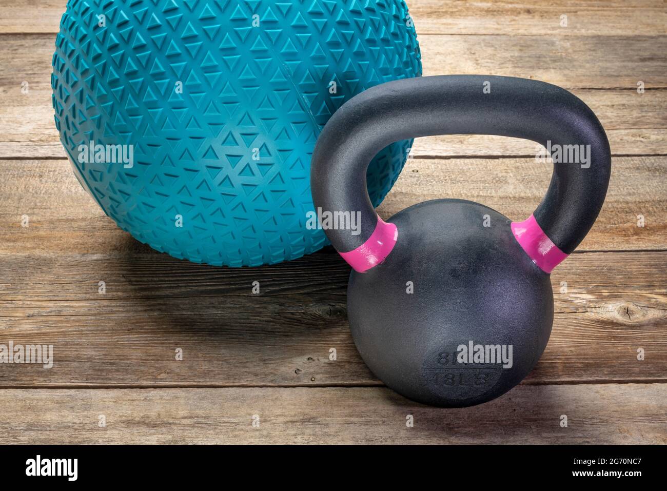 heavy rubber slam ball filled with sand and  small iron kettlebell on a rustic wood background,  training, exercise and fitness concept Stock Photo