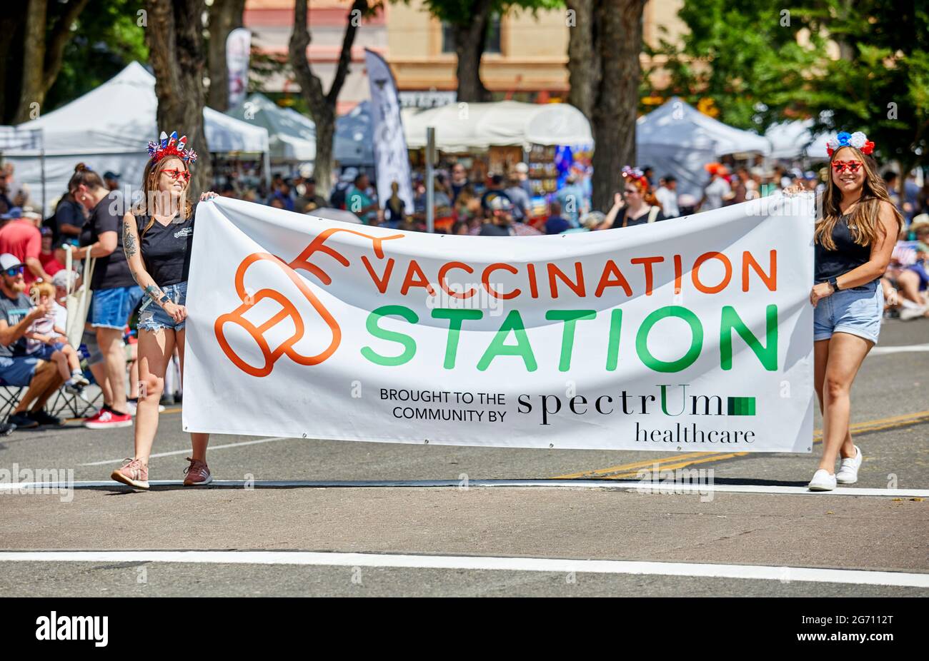 Prescott, Arizona, USA - July 3, 2021: Two girls carrying a vaccination station sign by Spectrum Health while marching in the 4th of July parade Stock Photo