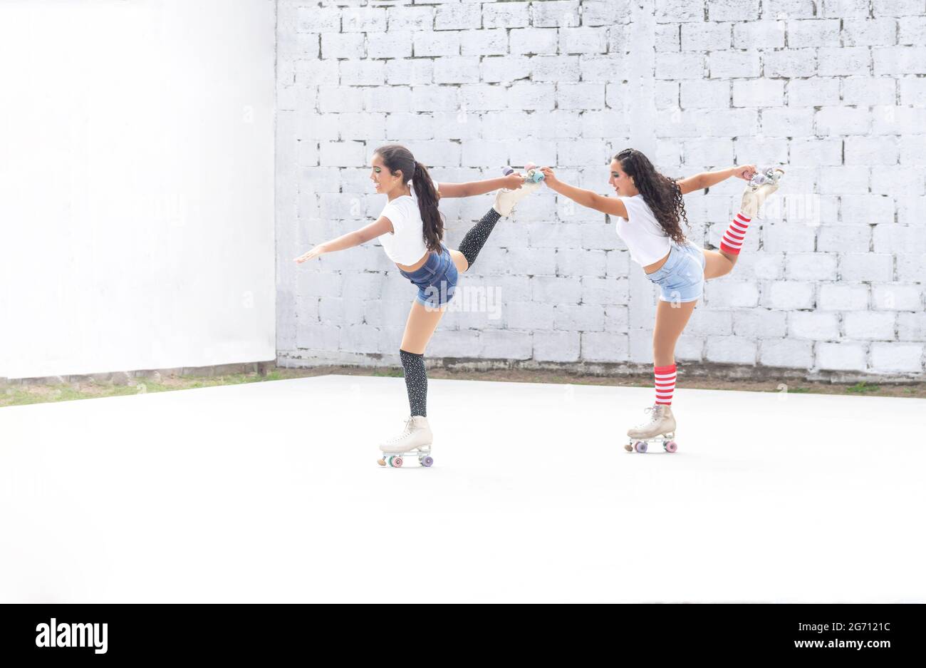 Two funny Latina teen girls doing a roller skating dance routine Stock Photo