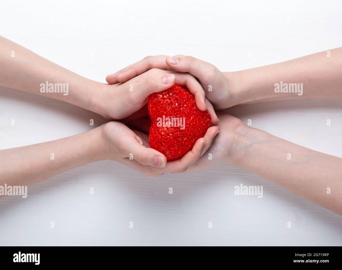 Red heart in the hands of a boy and a girl, on a white background Stock ...
