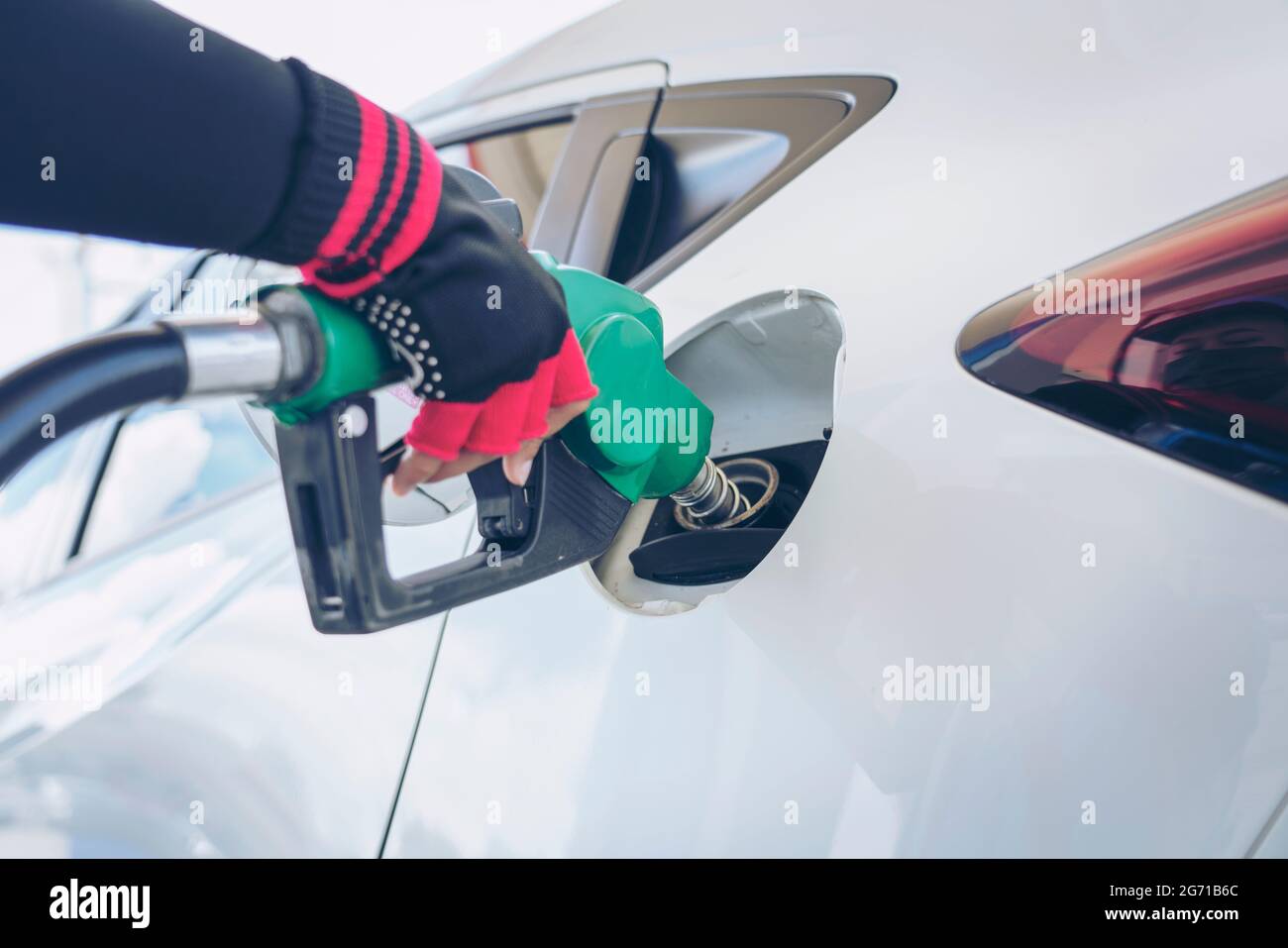 Vehicle fueling facility at petrol station. White car at gas station being filled with fuel