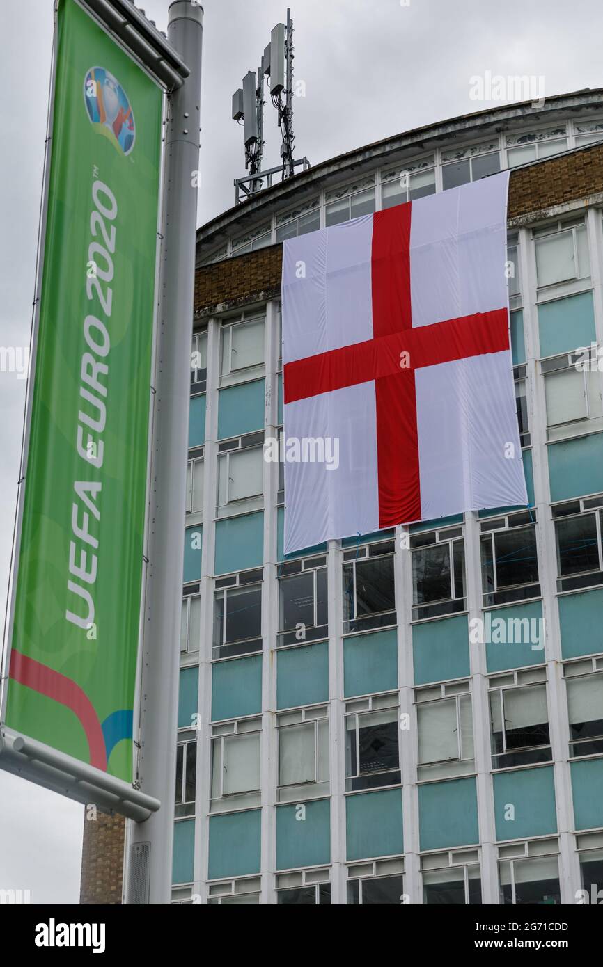 Wembley Park, UK. 10th July 2021.   Football's Coming Home,  Wembley Park is buzzing with excitement ahead of Sundays match and local businesses get behind the England team.     A giant England flag, the St Georges Cross, covers two floors of the College of North West London.   60,000 fans are set to descend to Wembley Park to watch England play Italy in the UEFA EURO 2020 Finals at Wembley Stadium on Sunday 11th July.  Amanda Rose/Alamy Live News Stock Photo