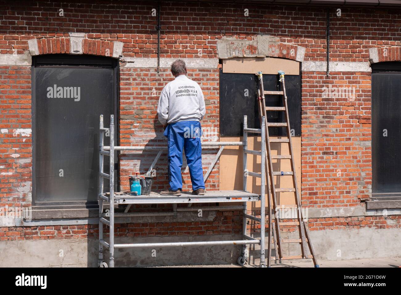 Sint Gillis Waas, Belgium, April 21, 2021, painter stands on a scaffold and inspects an old stone wall Stock Photo