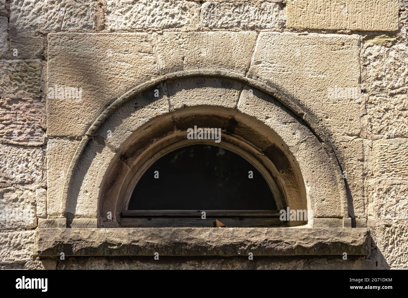 Symbolic image: round arch window in a wall structure. Stock Photo