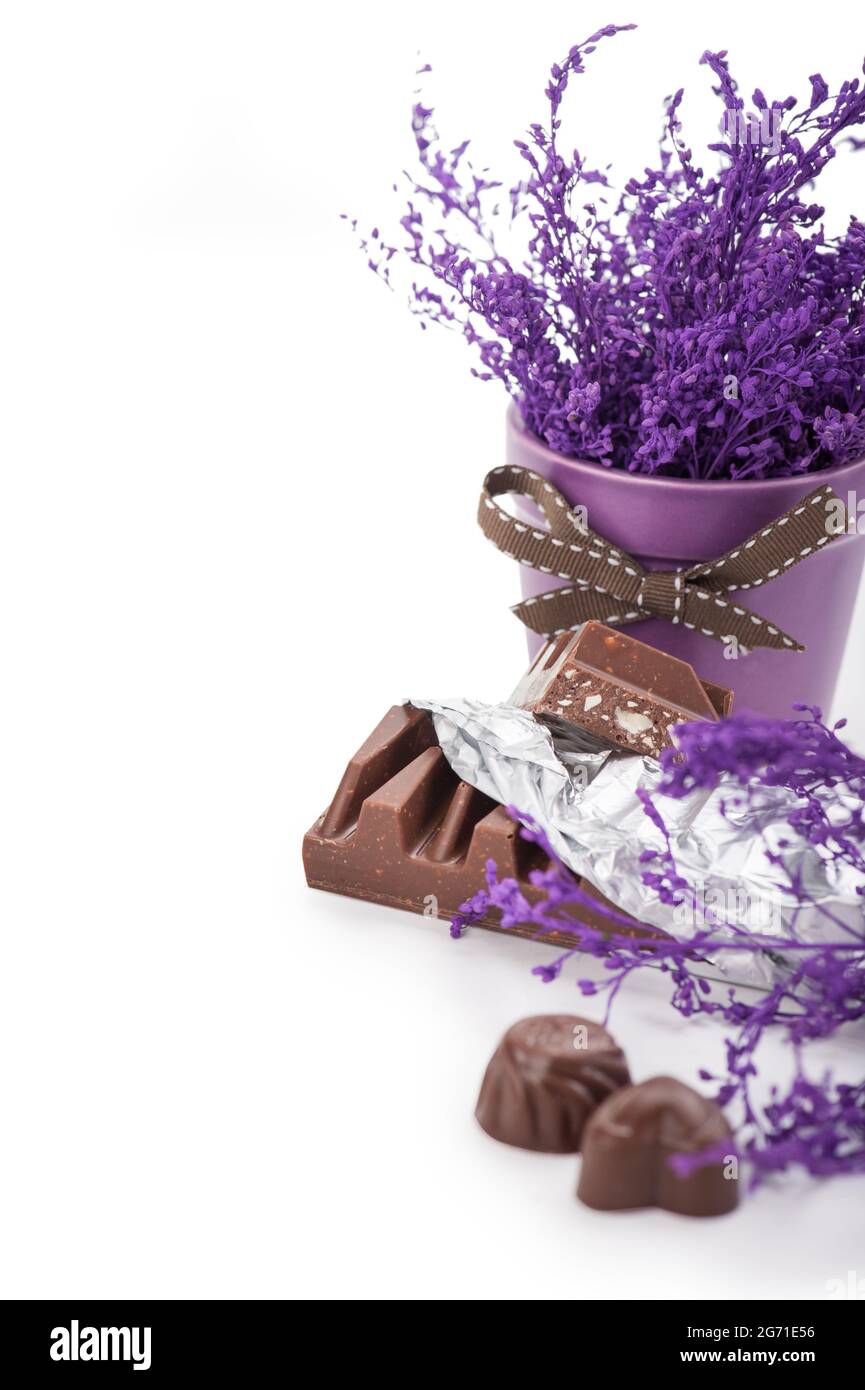 Still life with chocolate bar in foil, chocolates and pot flower Stock Photo