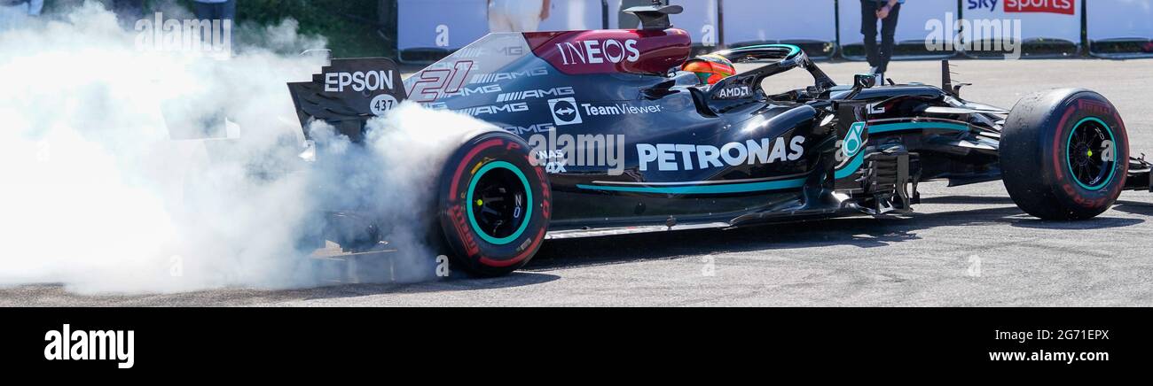 Mercedes Benz F1 W10 EQ Power+ racing car with smoking rear tyres burns rubber racing away. Petronas and Ineos sponsor the team: letterbox crop. Stock Photo