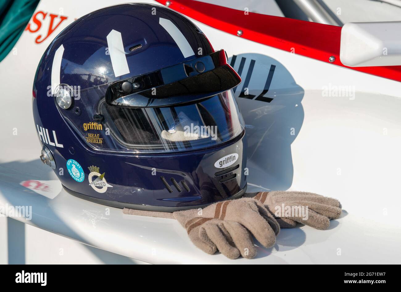 A navy blue crash helmet with white oar-shaped flashes and brown leather driving gloves worn by Graham Hill, F1 racing driver. Festival of Speed 2021 Stock Photo