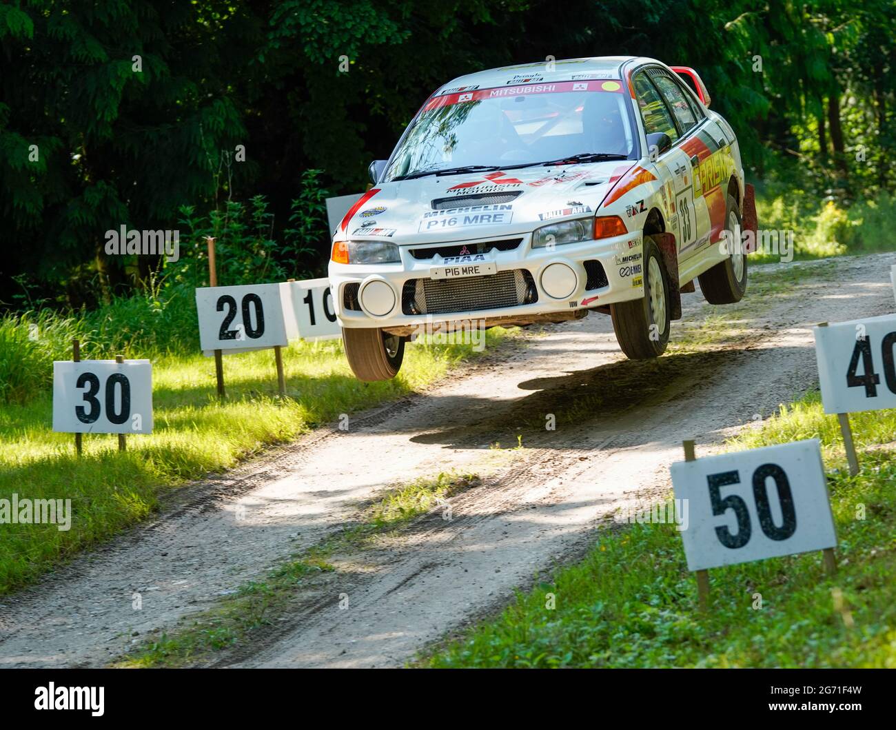Steve Chamberlain takes off over Forest Rally Stage jump in his Mitsubishi Evo IV with all four wheels off the ground. Goodwood Festival of Speed 2021 Stock Photo