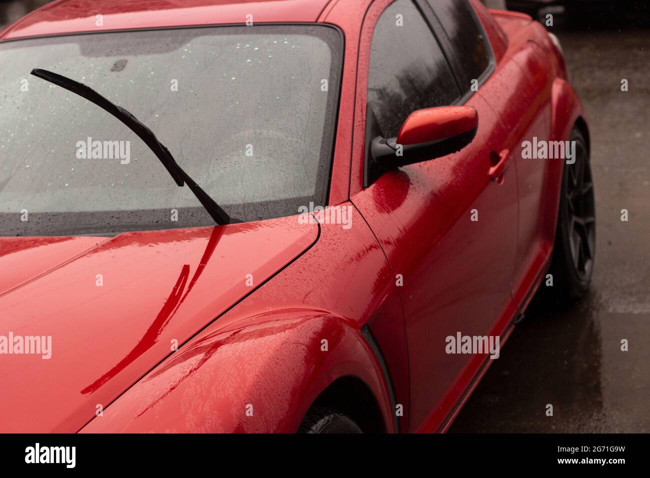 Red car in the parking lot. Car surface. Wet car after rain. Details of