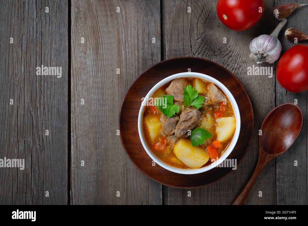 The main dish of fried pork with potatoes on old wooden table. Copy space Stock Photo