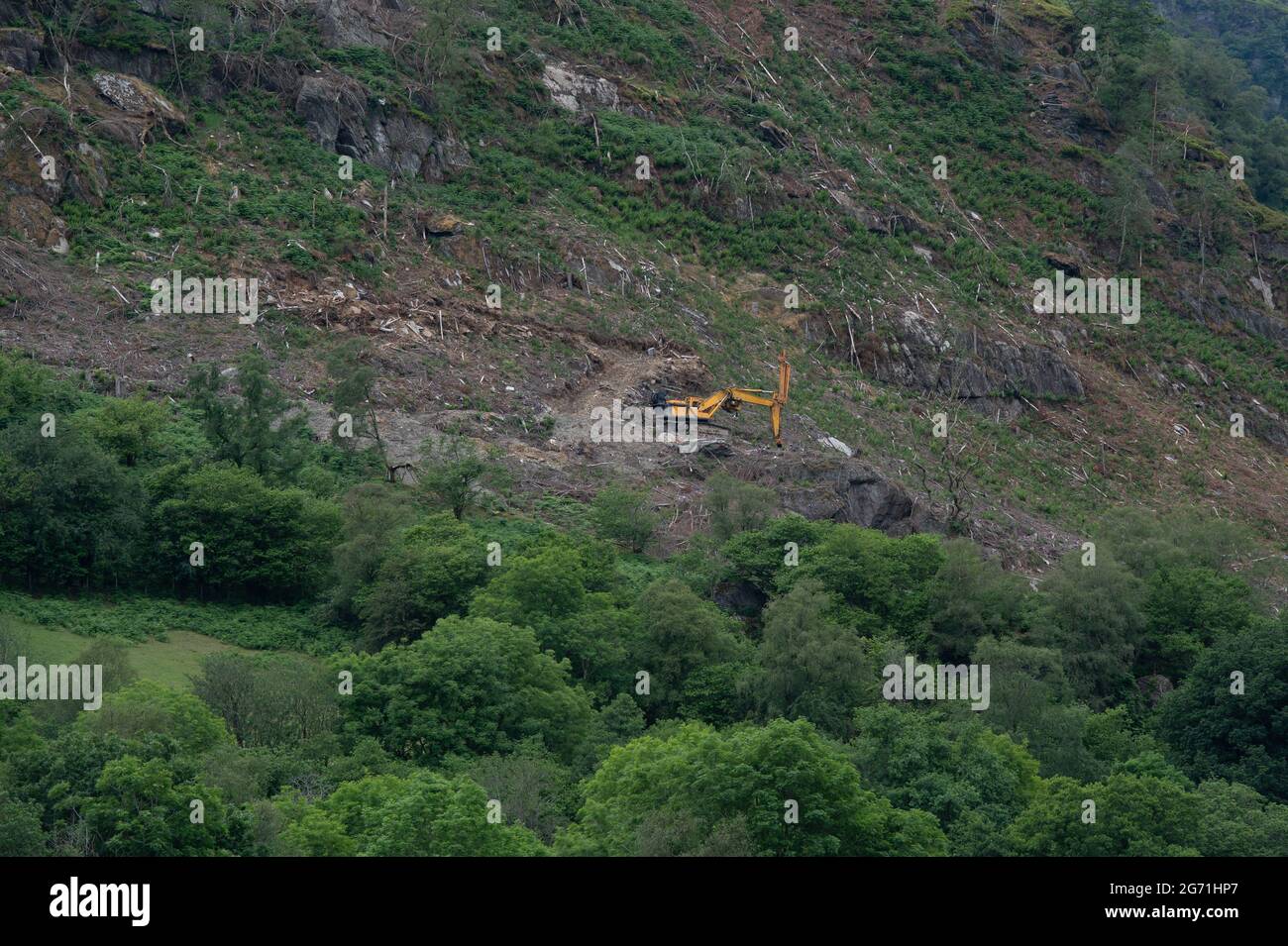 Yellow excavation vehicle working on the side of a mountain in the Brecon Beacons Stock Photo